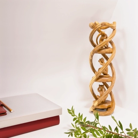 Elegant home office decor: Hand-carved 'Three Wise Monkeys' wooden totem displayed alongside books and greenery.